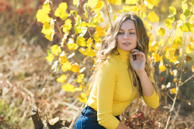 Junge attraktive blonde Frau draußen auf Herbsthintergrund. Herbstporträt der schönen stilvollen Frau.