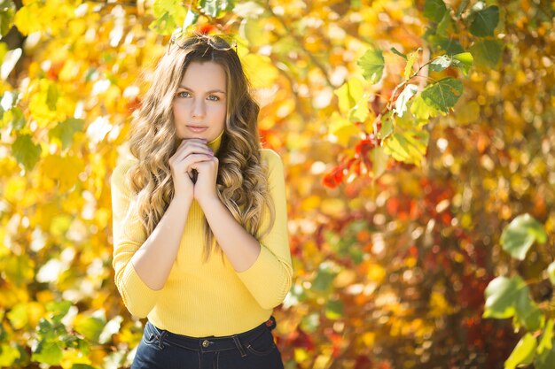 Junge attraktive blonde Frau draußen auf Herbsthintergrund. Herbstporträt der schönen stilvollen Frau.