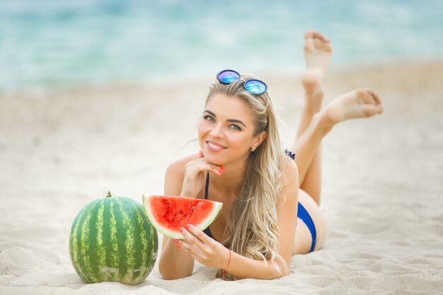 Junge attraktive Frau am Strand entspannend. Hübsche Frau mit Wassermelone. Nettes Mädchen im Freien