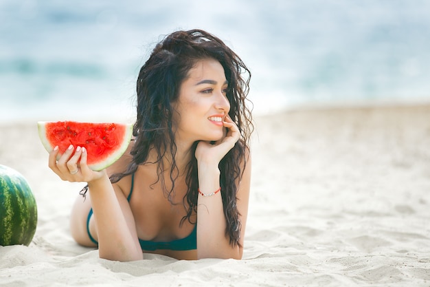Junge attraktive Frau am Strand entspannend. Hübsche Frau mit Wassermelone. Nettes Mädchen im Freien