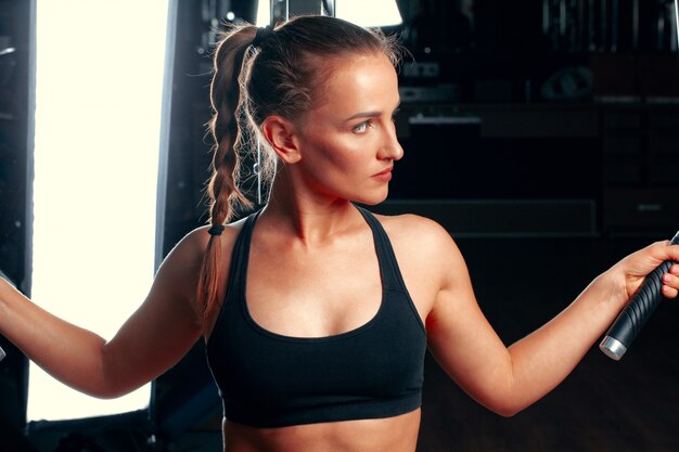 Junge attraktive Frau, die Übungen für Arme in einer Trainingsmaschine tut