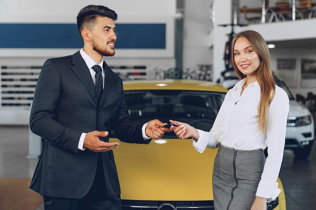 Junge attraktive Frau, die ein neues Auto im Autosalon nah oben kauft