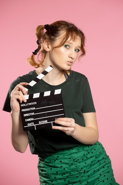 Junge attraktive Frau, die Filmklöppel jugendlich Mädchen in einem blauen Hemd und in einer Brille hält, die Klassiker hält