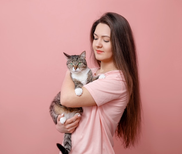 Junge attraktive frau, die katze in den händen umarmt