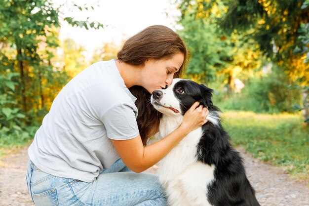 Junge attraktive Frau, die mit niedlichem Hündchen-Border-Collie auf Sommerhintergrund im Freien spielt Mädchen k