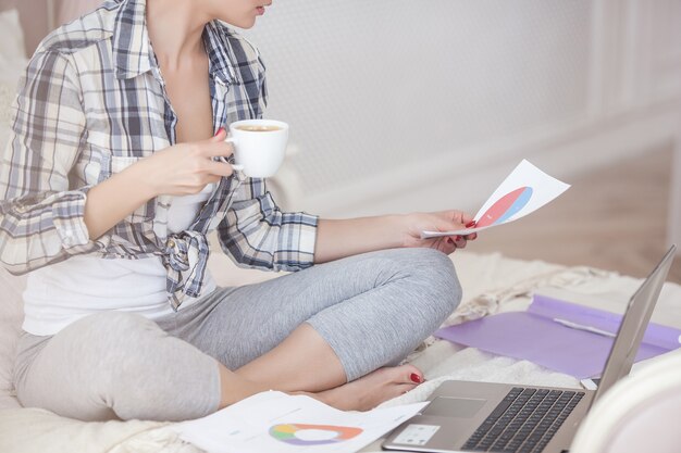 Junge attraktive Frau, die nach Hause am Laptop arbeitet