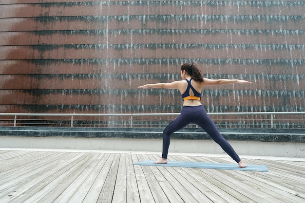 Junge attraktive Frau, die Yoga-Übungen im Park ausdehnt