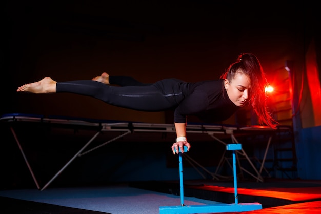 Junge attraktive Frau, die Yoga praktiziert, in der Hand-Balance-Übung, Handstand, Training, in Sportbekleidung, schwarzen Leggings und Top, drinnen in vollem Wachstum steht