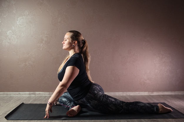 Junge attraktive Frau, die Yoga tragend Sportbekleidung praktiziert