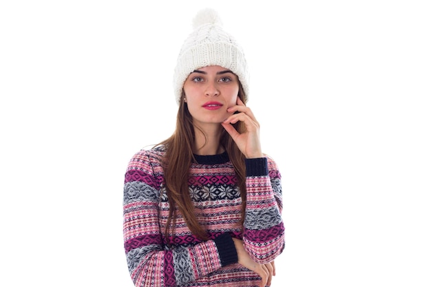 Junge attraktive Frau im purpurroten Pullover und im weißen Hut auf weißem Hintergrund im Studio