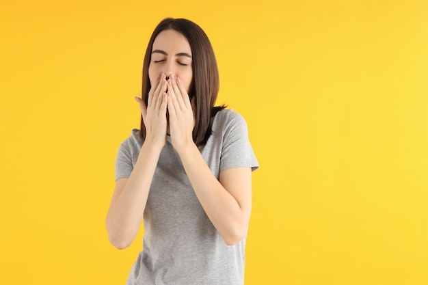 Junge attraktive Frau im T-Shirt auf gelbem Hintergrund