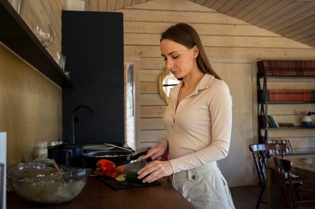 Junge attraktive Frau kocht gerne gesundes Essen in einem Topf auf dem Herd in der heimischen Küche