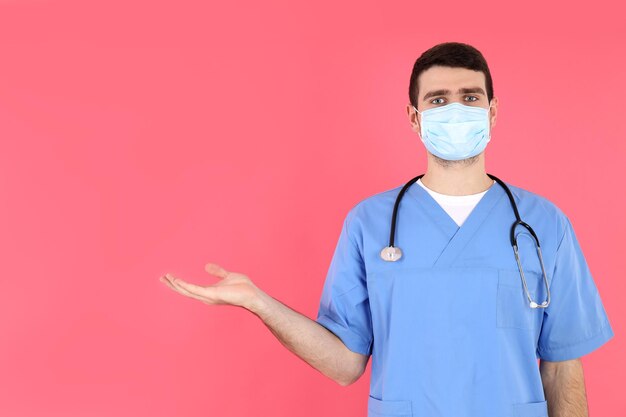 Junge attraktive Krankenpfleger auf rosa Hintergrund