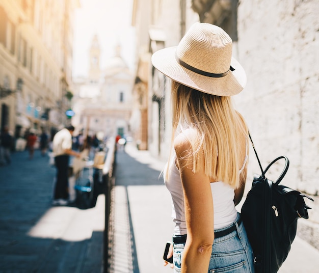 Foto junge attraktive lächelnde touristin mit hut, die in den sommerferien die neue stadt europas erkundet