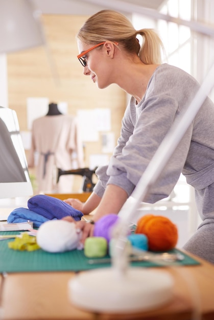 Junge attraktive Modedesignerinnen, die sich auf den Schreibtisch stützen und mit einem Laptop arbeiten