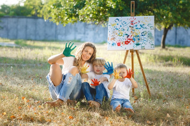 Junge attraktive Mutter, die Spaß mit ihren Kindern am Park hat. Fröhliche Familie, die Spaß im Freien hat. Mama spielt mit ihren Kindern.