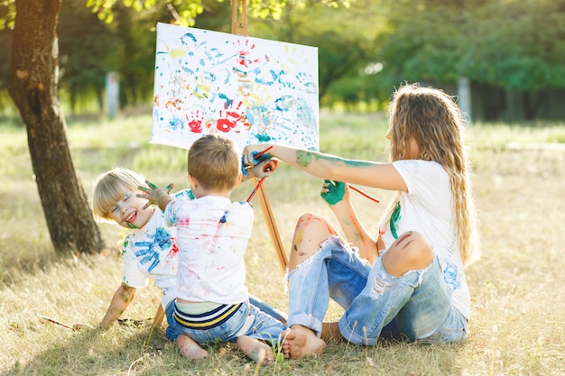 Junge attraktive Mutter, die Spaß mit ihren Kindern am Park hat. Fröhliche Familie, die Spaß im Freien hat. Mama spielt mit ihren Kindern.