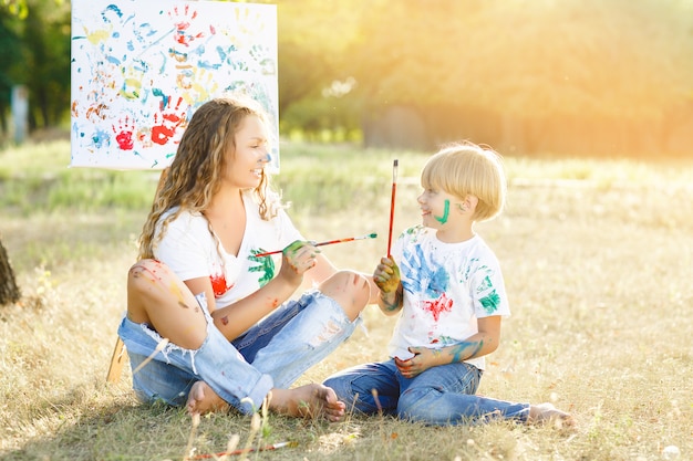 Junge attraktive Mutter, die Spaß mit ihren Kindern am Park hat. Fröhliche Familie, die Spaß im Freien hat. Mama spielt mit ihren Kindern.