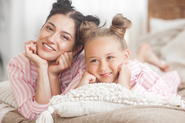 Junge attraktive Mutter und ihre kleine Tochter, die Spaß an der Pyjama-Party haben. Familie am Morgen