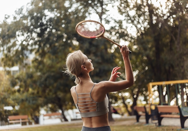 Junge attraktive Sportfrau, die Badminton im Park spielt