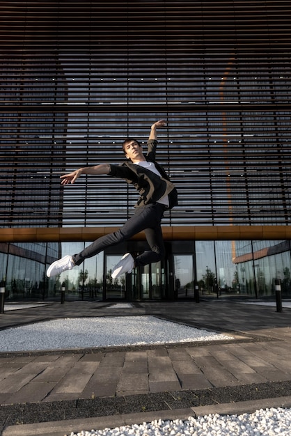 Junge attraktive Tänzerin in lässigem Stoff, die Ballettsprünge auf dem städtischen Hintergrund macht Zeitgenössischer Tanz, moderne Choreographie