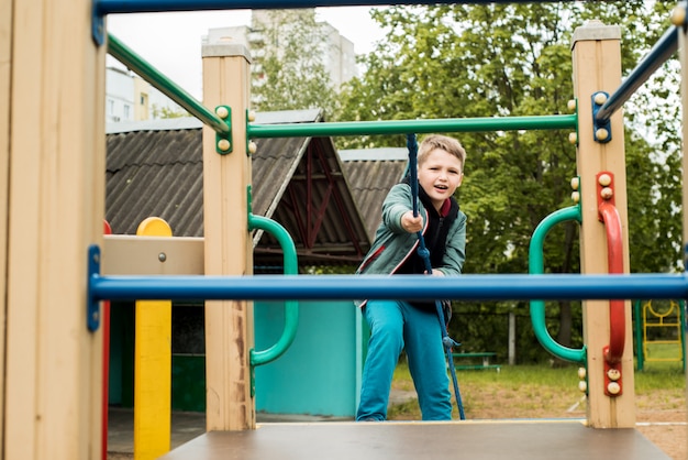 Junge auf dem Spielplatz. Seilwettbewerb. hochklettern. glückliche Kindheit im Sommer. Leistung und Streben nach Erfolg. der Spielplatz im Freien