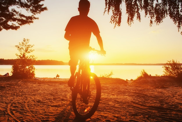 Junge auf einem Fahrrad bei Sonnenuntergang