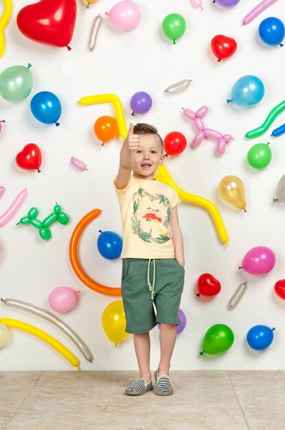 Junge auf weißem Hintergrund mit bunten Luftballons Junge hebt seine Hände auf weißem Hintergrund