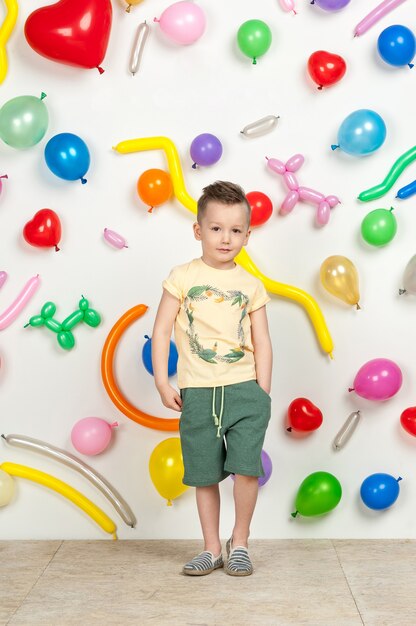 Junge auf weißem Hintergrund mit bunten Luftballons Junge in einem Tanktop und Shorts