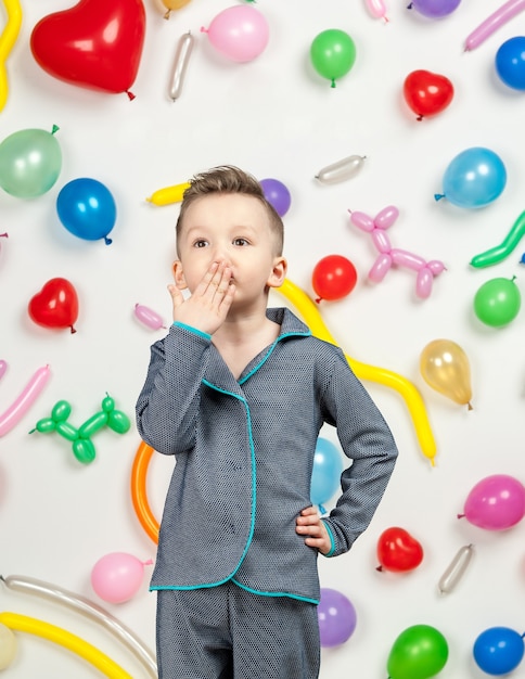 Junge auf weißem Hintergrund mit bunten Luftballons Junge sendet einen Luftkuss auf weißem Hintergrund