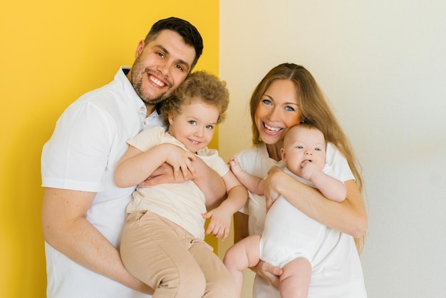 Junge aufrichtige Familie, in der ein glücklicher Vater und eine glückliche Mutter ihre lieben Kinder in den Armen halten Familienfoto-Shooting im Studio