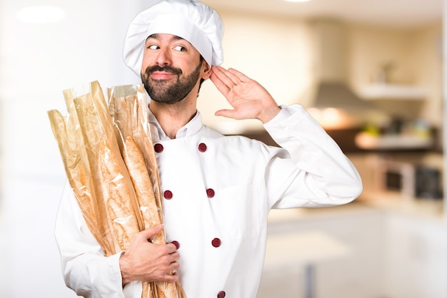 Junge Bäcker halten etwas Brot und hören etwas in der Küche