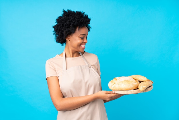 Junge Bäckerfrau über lokalisierter blauer Wand