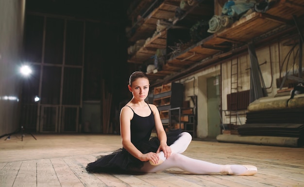 Junge Ballerina im schwarzen Kleid trainiert hinter den Kulissen.