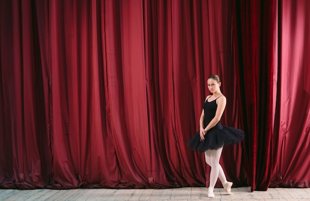 Junge Ballerina im schwarzen Kleid zieht hinter die Kulissen.
