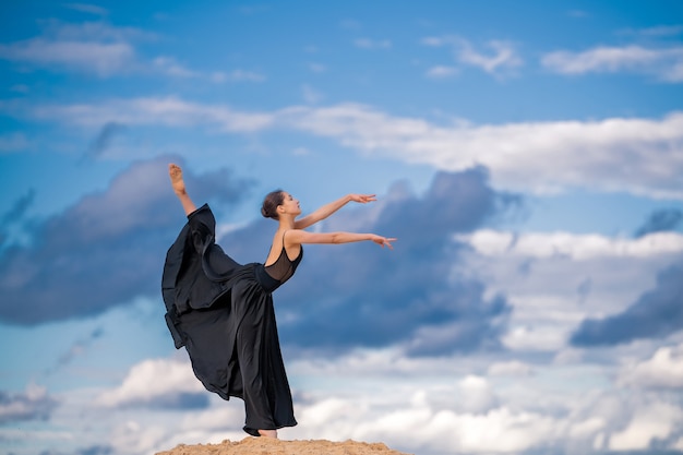 Junge Ballerina in einem schwarzen langen Kleid tanzen