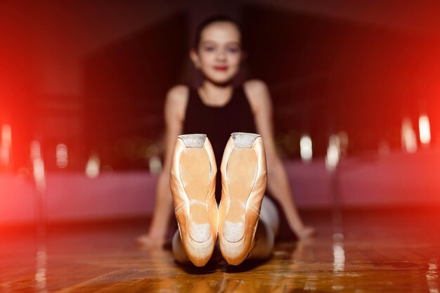 Junge Ballerina mit sitzt im Tanzstudio Die Tänzerin trägt Trikot Klassische Kunst und begabtes Kind Mädchen mit Ballettschuhen Closeup