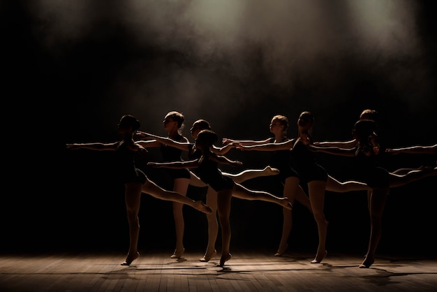 Junge Ballerinas, die in der Ballettklasse proben. Sie führen unterschiedliche choreografische Übungen durch und stehen in unterschiedlichen Positionen.