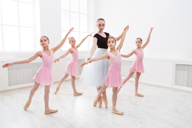 Junge Ballettlehrer und Studentenballerinas im Tanzunterricht. Mädchen sind in der Ballettschule mit Choreografien beschäftigt.