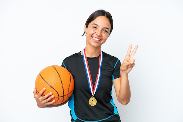 Junge Basketballspielerfrau lokalisiert auf dem weißen Hintergrund, der Siegeszeichen lächelt und zeigt