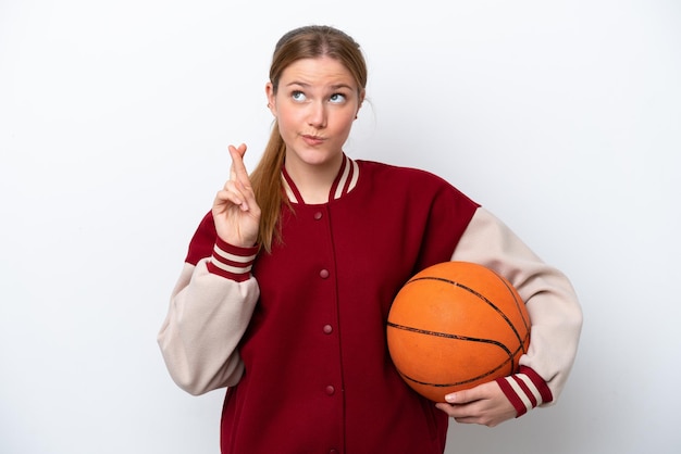 Junge Basketballspielerfrau lokalisiert auf weißem Hintergrund mit den Daumen, die sich kreuzen und das Beste wünschen