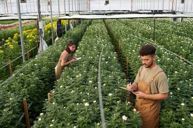 Junge Bauer macht Notizen in einem Dokument, während er unter blühenden Blumen steht