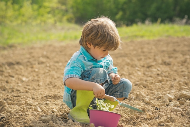 Junge Bauernkleinkinder arbeiten im Blumenpark Tag der Erde Kinderbauern auf dem Bauernhof mit Landschaft