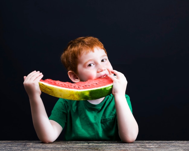 Junge beißt eine rote Wassermelone