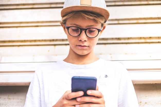 Junge benutzt sein Handy an der Wand