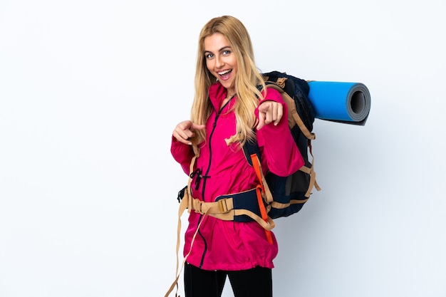 Junge Bergsteigerfrau mit einem großen Rucksack isoliert zeigt Finger auf Sie