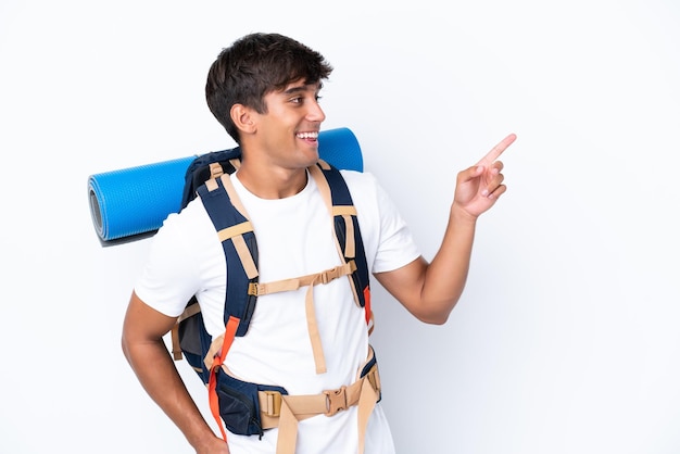 Junge Bergsteigerfrau mit einem großen Rucksack über isoliertem weißem Hintergrund, der mit dem Finger zur Seite zeigt und ein Produkt präsentiert