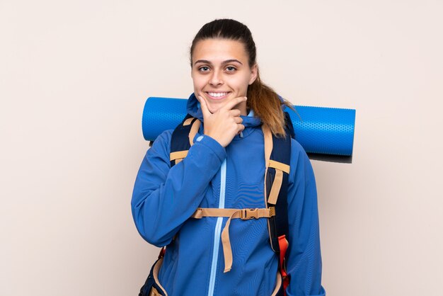 Junge Bergsteigerfrau mit einem großen Rucksack über lokalisiertem Wandlachen