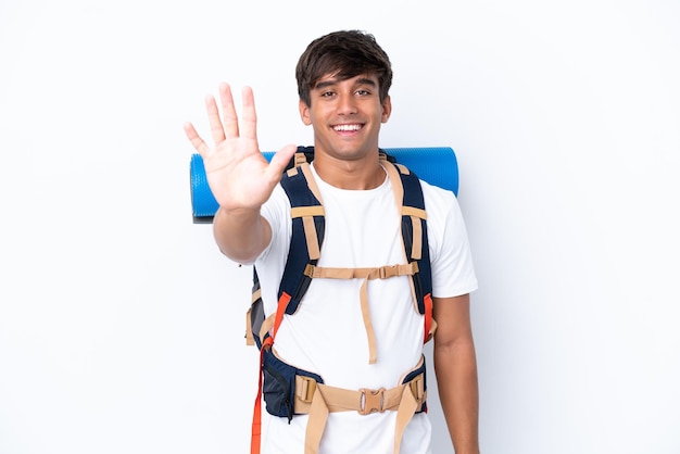 Junge Bergsteigerfrau mit einem großen Rucksack über lokalisiertem weißem Hintergrund, der fünf mit den Fingern zählt