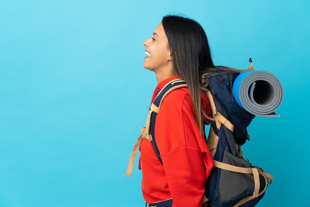 Junge Bergsteigerfrau mit Rucksack, der in seitlicher Position lacht